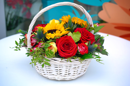 A vibrant arrangement of flowers in a basket sits on a table, providing a splash of color and beauty.