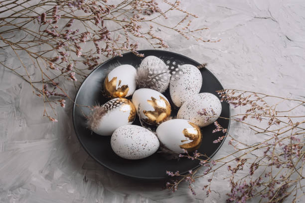 istock Black plate with Easter eggs and flowers on textured gray background. Top view 2058352595