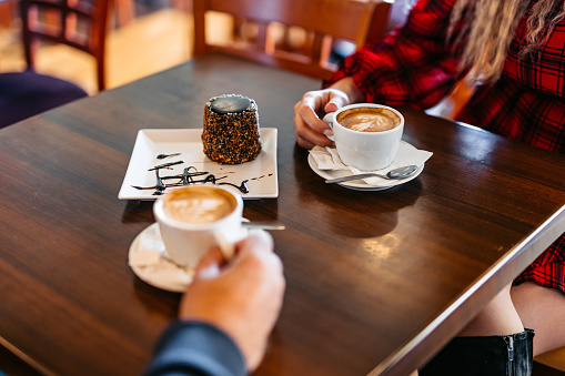 Young couple drinking coffee and eating a desert in a café. Close-up.
