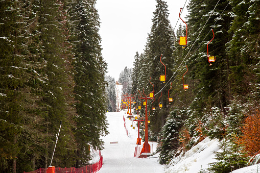 One-sit colorful ski lift between snowy forest.