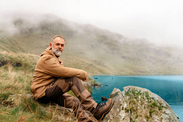 bearded man reaching the destination and on the top of mountain at sunset on autumn day travel lifestyle concept the national park lake district in england - english lake district orienteering hiking mountain стоковые фото и изображения