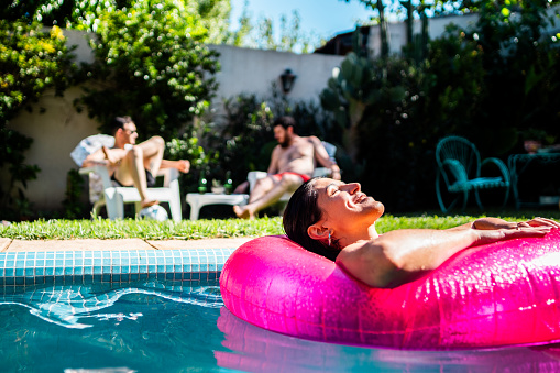 Young woman relaxing on inflatable floating ring in the swimming pool at home