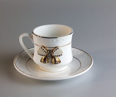 Empty antique porcelain coffee cup with bow on white background.
