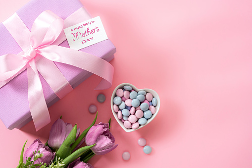 Mother's Day design concept background with tulips, candies and gift on pink background. High resolution 42Mp studio digital capture taken with Sony A7rII and Sony FE 90mm f2.8 macro G OSS lens