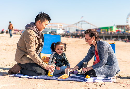 A young family together on the beach at Santa Monica, enjoying a picnic together.
