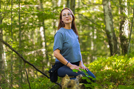 Woman in the woods surrounded by plants and illuminated by natural sunlight
