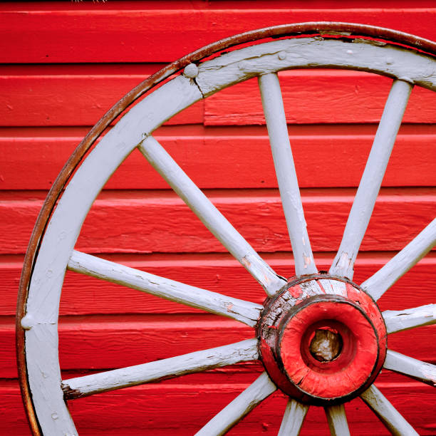 istock Old Retro Worn Wagon Wheel by Painted Red Wall 2058434379