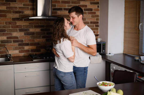 istock Happy young couple smiling and dancing in the kitchen while preparing dinner. Loving man and woman having fun at home. 2058451078