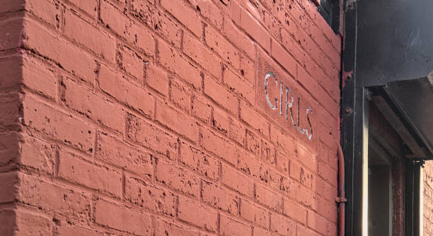 公園内の古い建物のレディースルームの赤レンガの壁に女の子のサイン(トイレ、バスルーム、トイレ、洗面所、水洗トイレ、女性用トイレの入り口)