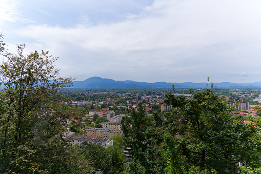 Aerial view of City of Ljubljana seen from castle hill with skyline and mountain panorama in the background on a cloudy summer day. Photo taken August 9th, 2023, Ljubljana, Slovenia.