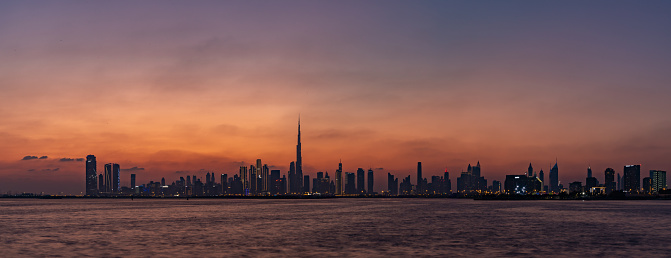 Dubai, United Arab Emirates - November 5, 2023: A panorama and colorful picture of Dubai at sunset, with the Burj Khalifa towering the other high rises.