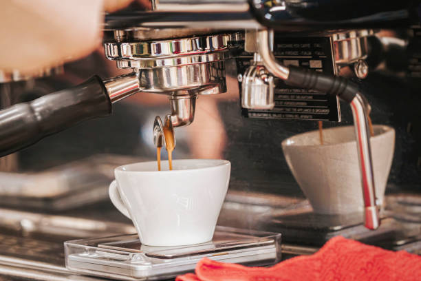 istock Pouring espresso coffee from coffee machine into porcelain cup close up 2058559445