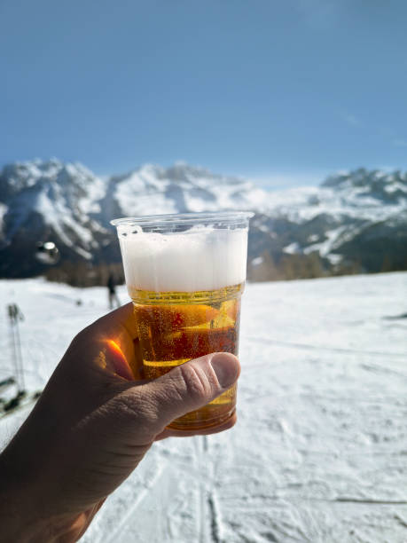 крупный план руки, держащей бокал пива на горнолыжном курорте - beer ski apres ski snow стоковые фото и изображения