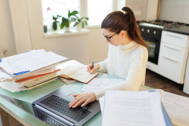 istock A woman with glasses on her job, utilizing her laptop and managing documents efficiently in a home 2058565792
