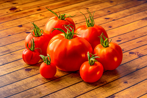 Red fresh tomatoes on wooden table over bokeh background