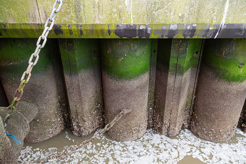 Sea pier on steel supports at low tide, build-up and corrosion on the supports.