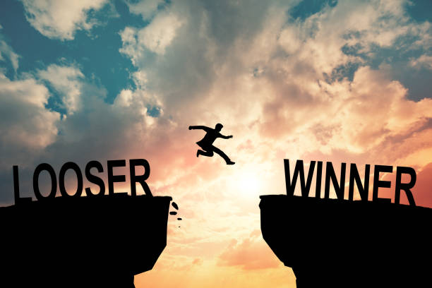 istock Silhouette young man jumping and raising up her hand about winner concept on winner text over a beautiful sunset or sunrise at the sea. background for success winner and looser concept. 2058715974