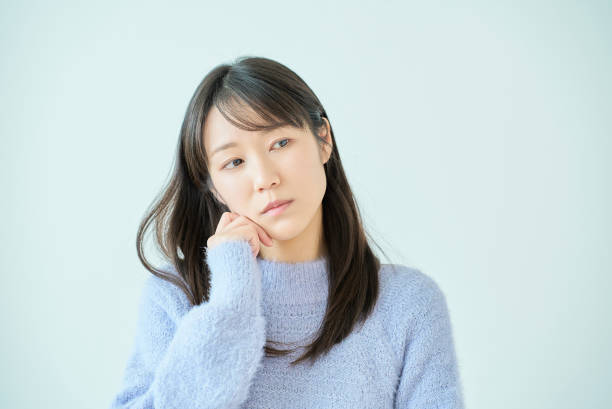 顎に手を当てて考えている若い女性 - 質問 ストックフォトと画像