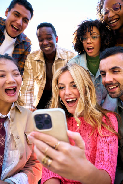 istock A group of happy amazed humans friends in outerwear using mobile smiling watching something funny 2058734063