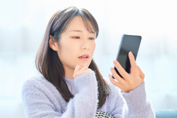 istock Young woman looking at her smartphone with a disappointed expression 2058743824