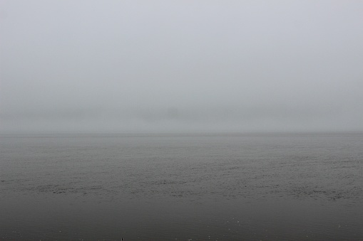 Line of thick fog covering the New Jersey coastline and rain falling on the Hudson River as seen from Manhattan, New York City