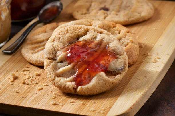 A oversized peanut butter cookie stacked on top of a baking sheet on top of more cookies.