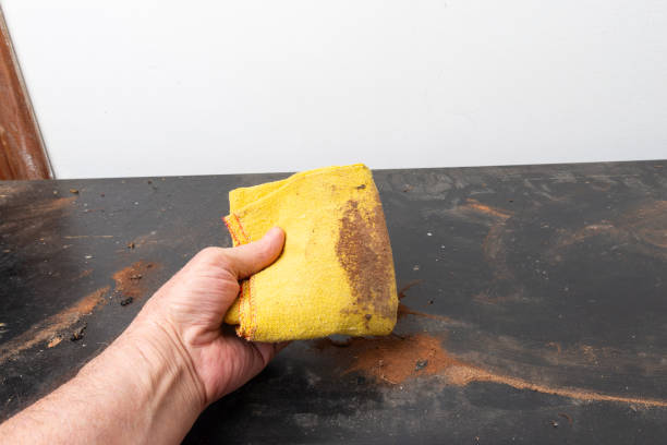 An unrecognized person cleaning coffee mark from the marble in the kitchen, using dish protective gloves and dishcloth.