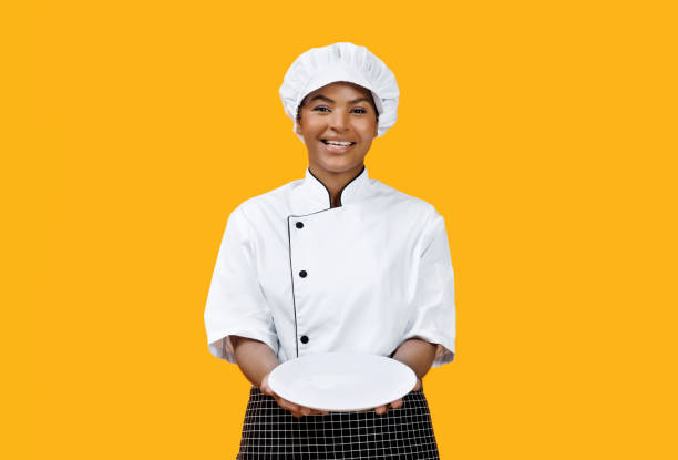 istock Cheerful black female chef proudly presenting empty white plate 2058874299
