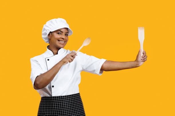 istock Friendly black female chef with radiant smile holding cooking utensils 2058874302