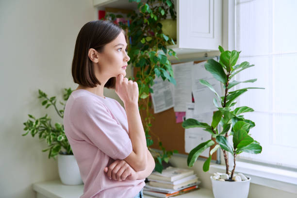 istock Serious young woman looking out the window, in home interior 2058923052