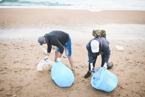 istock men collecting trash on the beach 2058925733