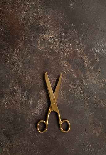 Golden scissors on the brown background.