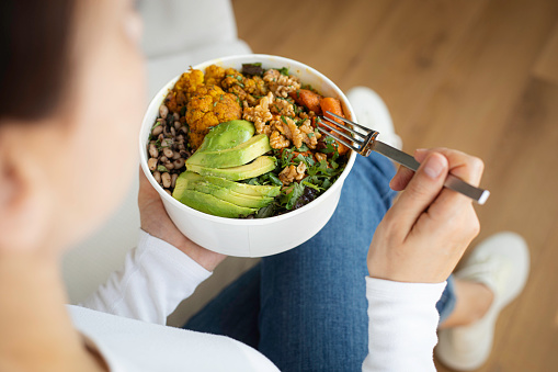 Woman eating fresh salad, avocado, beans and vegetables.