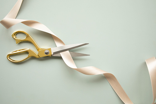 Golden scissors cutting a ribbon.