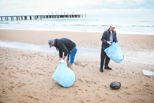 istock men collecting trash on the beach 2058932672