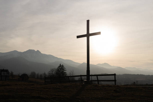 religion theme, view of catholic cross silhouette, with fantastic sunset and mountains as background. toned image - old cross shape stone weathered стоковые фото и изображения