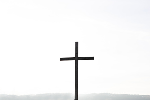 Religion theme, view of catholic cross silhouette, on white background. Copy space.