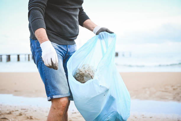 istock man collecting trash on the beach 2058948528