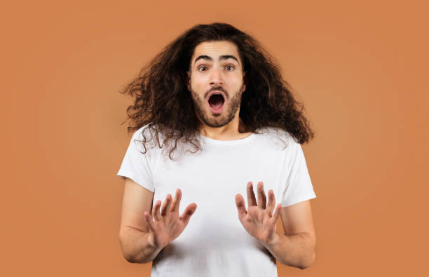 istock Shocked guy with curly hair showing stop gesture, beige backdrop 2058952800