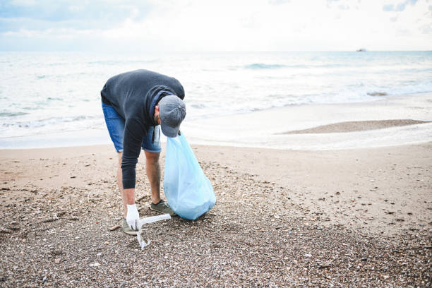 istock man collecting trash on the beach 2058953874