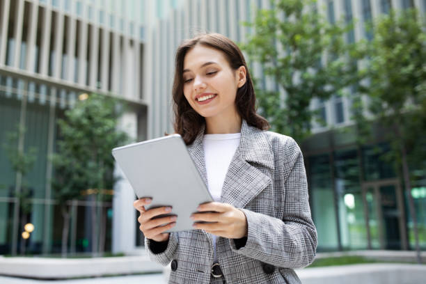 istock business lady happily browsing on digital tablet computer, standing outside 2058959756