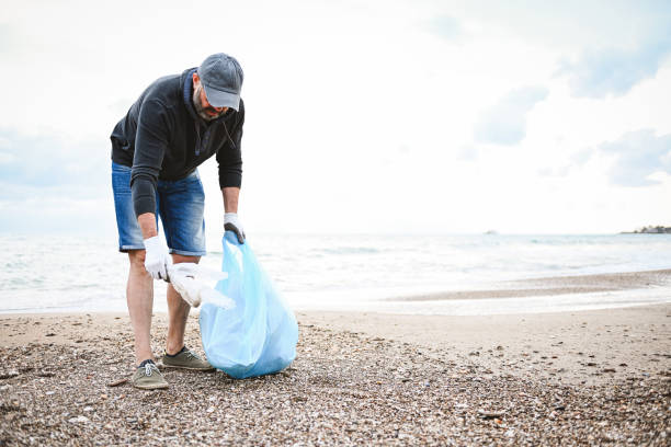 istock man collecting trash on the beach 2058969317