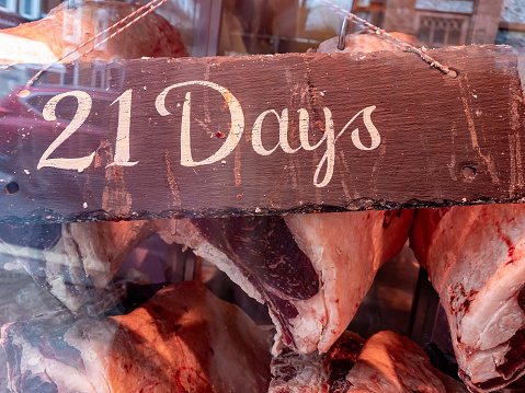 21 days dry aged hung beef on display in the widow of a butcher retail store.
