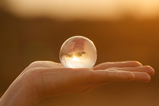 A close up of a pair of male hands surrounding a crystal ball on an isolated dark studio background