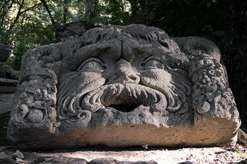 Bomarzo, Italy - 10 08 2023: Face figure sculptured in giant rocks in Bomarzo Sacro Bosco Park in Italy