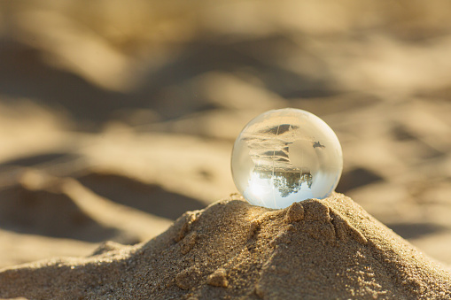 Glass globe lying on sand. Planet Earth.
