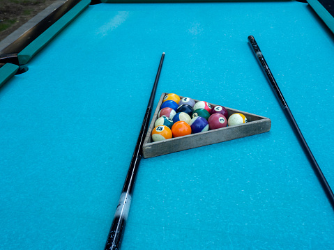 Pool table on the street. Outdoor game. In a park and resort. Worn cloth. Triangle. Cue