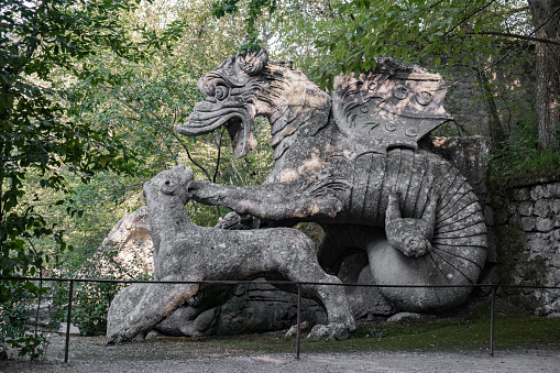 Bomarzo, Italy - 10 08 2023: Dragon figure sculptured in giant rocks in Bomarzo Sacro Bosco Park in Italy