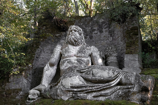 Bomarzo, Italy - 10 08 2023: Laying man figure sculptured in giant rocks in Bomarzo Sacro Bosco Park in Italy
