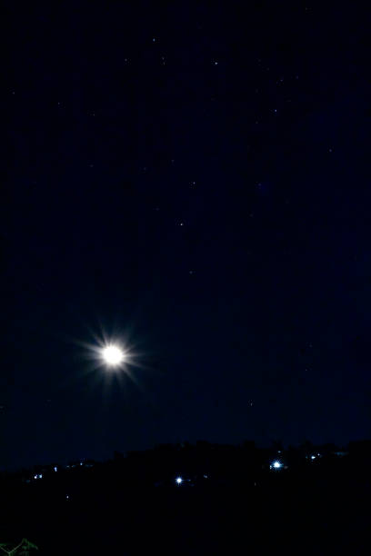 istock Moon with stars in night sky with lights on a hill. 2059019542